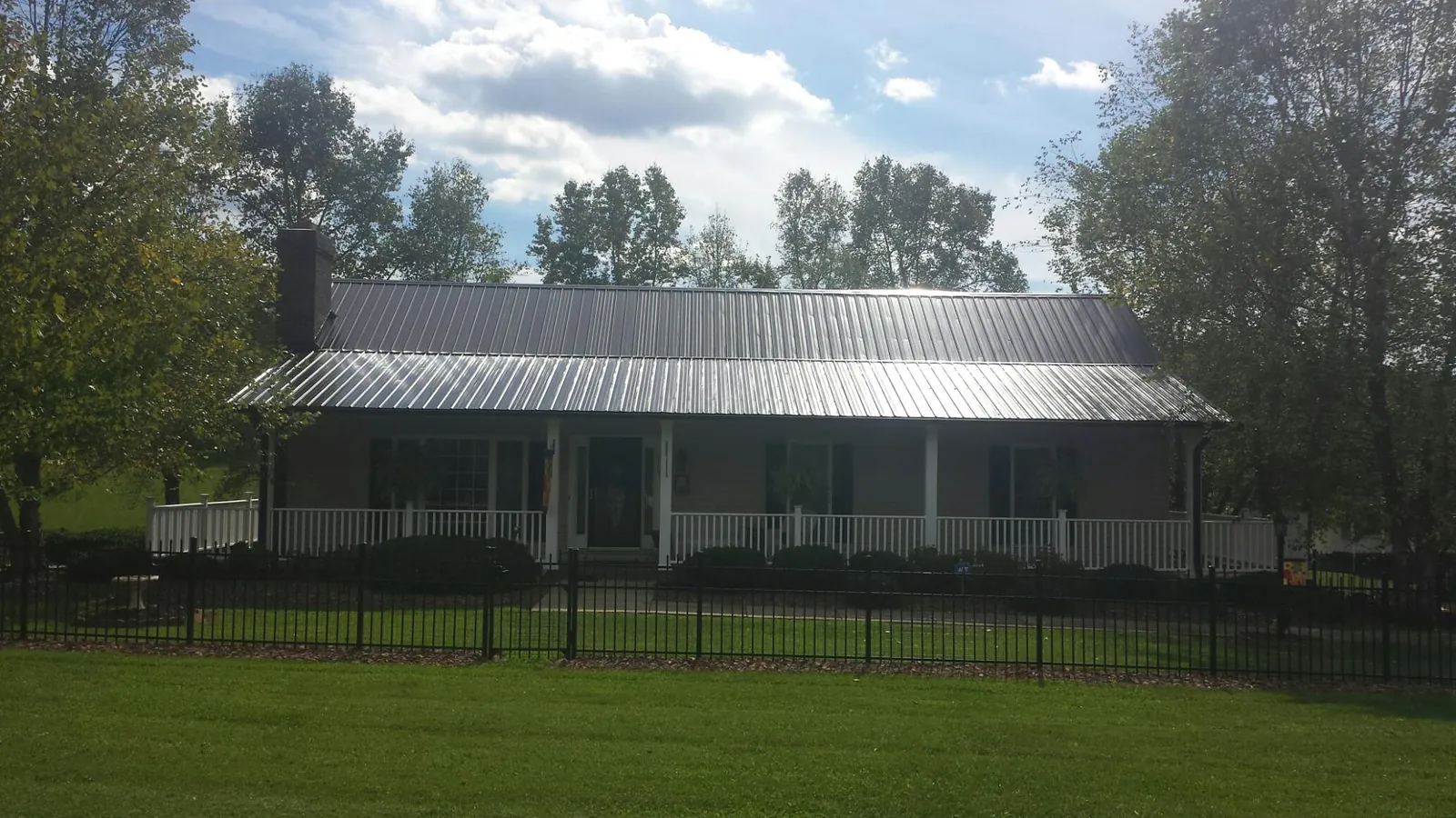 Gray metal roof on a brick ranch with a full width front porch — Gutter Guard Installation work by our crew in Southington