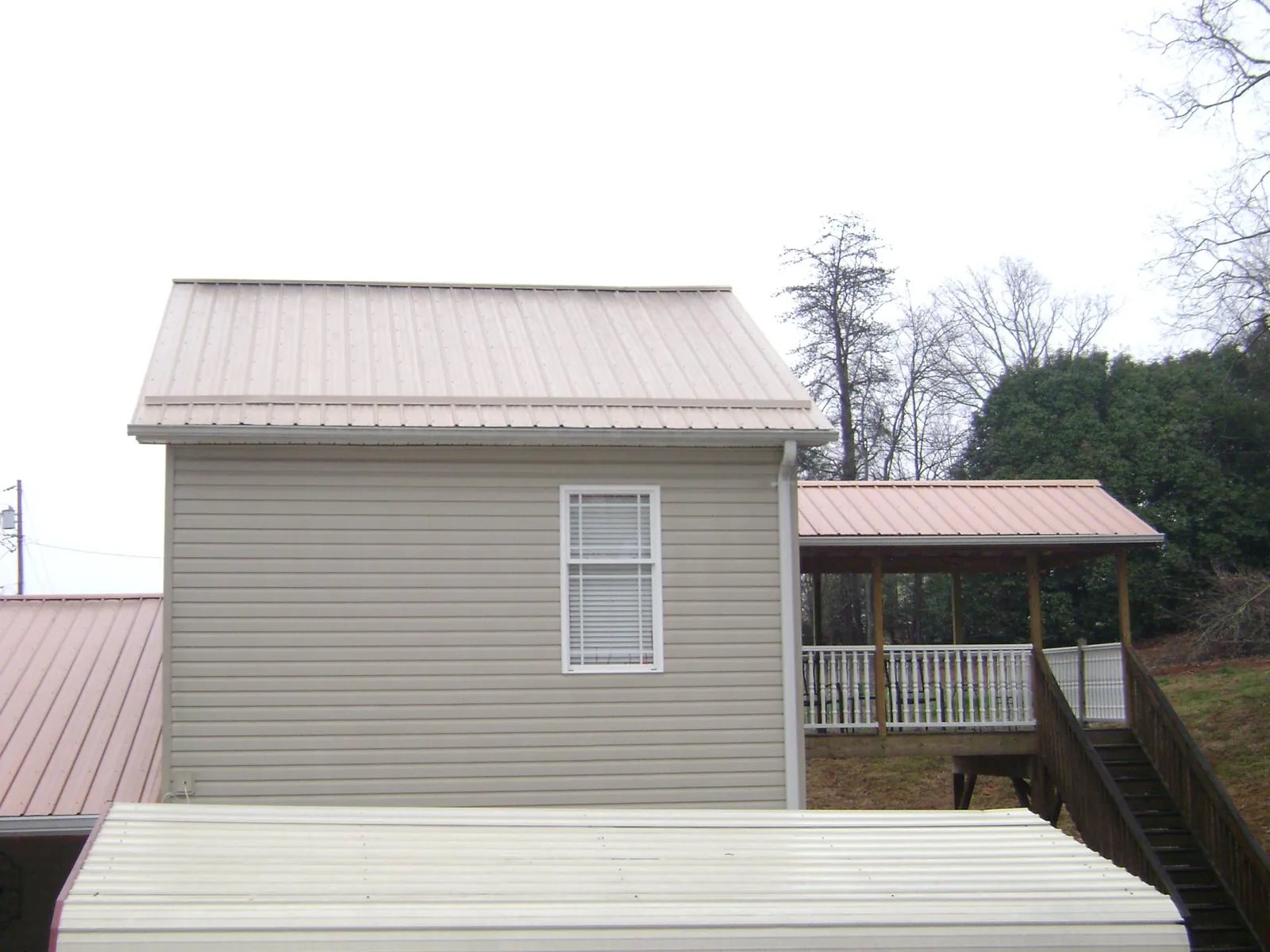 Tan metal roofs on a two story addition and attached porch, from a Roof Replacement job in Southington